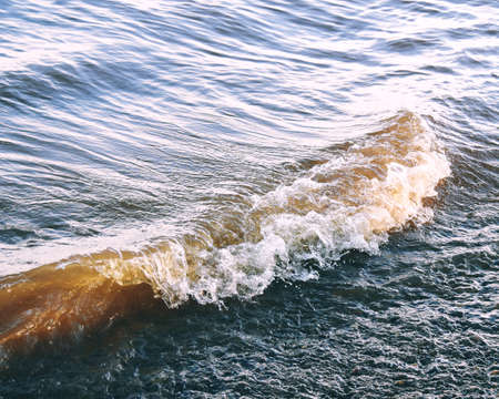 splashes of waves and foam hitting the shoreの写真素材