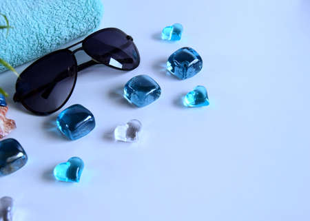 Beautiful composition of a towel with spa stones and sunglasses on a blue background. Holiday...