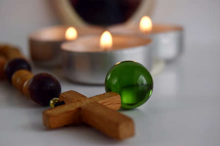 mystical still life. burning candles, a magic glass ball and a rosary on a light background. the...