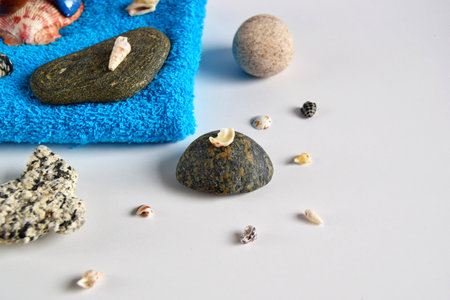 Beautiful composition of a towel with stones, shells and spa sunglasses on a light background....