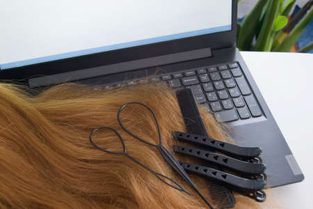 Online training for a hairdresser. Barber barber tools on laptop on light background, copy space.