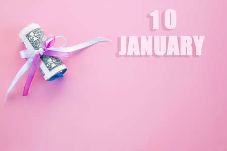 calendar date on pink background with rolled up dollar bills pinned by pink and blue ribbon with copy space. January 10 is the tenth day of the month.の写真素材