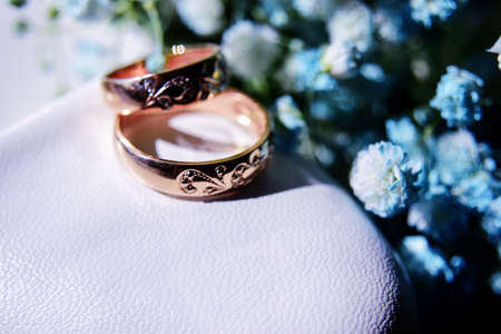 gold wedding rings on the brides white shoe and a beautiful bouquet of blue gypsophila in the...