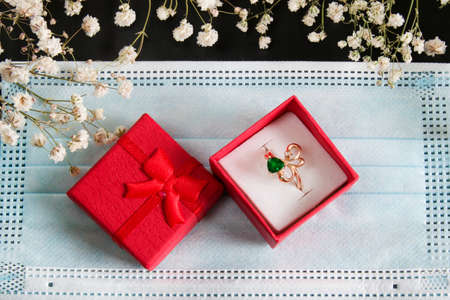 ring in a gift box, flowers on a medical mask. wedding in coronavirus concept close upの写真素材