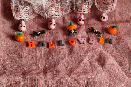 Halloween concept with pumpkin, skeleton and toy spiders on crumpled gray backgroundの写真素材