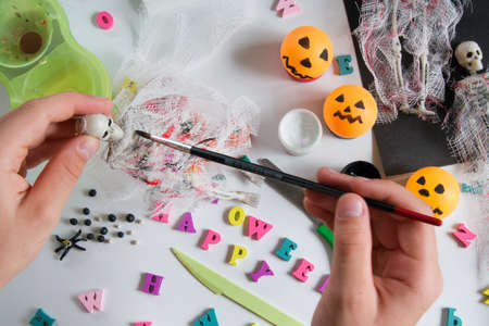 Childrens hands paint on the bandage with paint. Paper, bandage, plasticine with paints on a wooden table. Halloween postcard spider and cobweb, ghostly skeletons. Crafts for childrenの写真素材