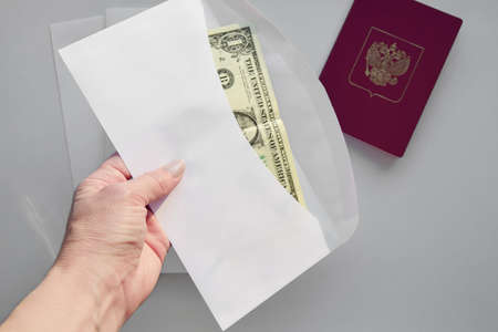 Womans hand with white envelope with money with passport, money accumulation and corruption concept.