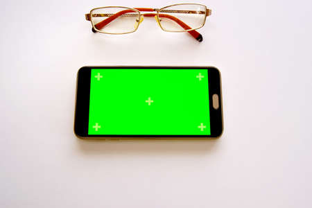 One glasses with smartphone green screen mockup, top view on gray background.