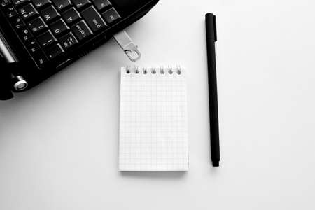 Technology concept of notepad and pen, laptop and flash drive.