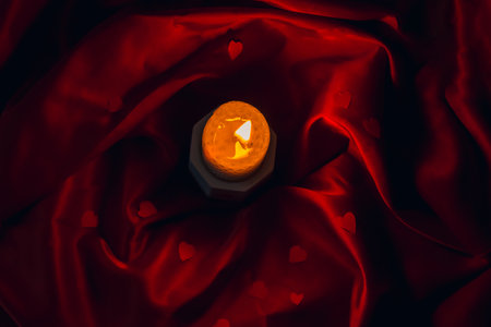Celebration of Valentine's Day, International Women's Day on March 8, Mother's Day. White burning candle, red small hearts, postcard on a red background. Table decor for a festive dinner, romantic atmosphere. flat layの写真素材