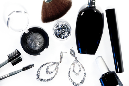 Collection with cosmetics tools. Fashion evening decorative set with make-up accessories, black nail polish, silver eyeshadows, mascara, luxury perfume and brilliants earrings. Cosmetic & makeupの写真素材