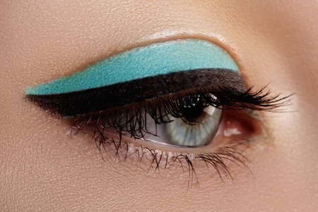 Beautiful macro shot of female eye with makeup. Perfect shape of eyebrows, blue eyeliner. Cosmetics and make-up.の写真素材