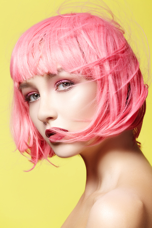Young model in pink wig. Beautiful model with fashion makeup. Bright spring look. Sexy hair color, medium hairstyle on yellow backgroundの写真素材