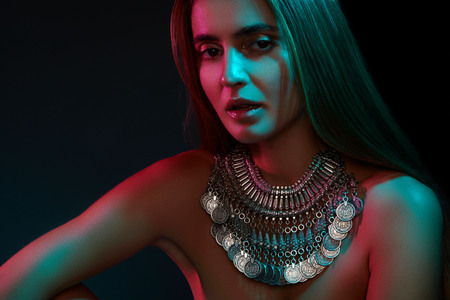Beautiful woman in a necklace. Model in jewelry from silver. Beautiful indian jewellery. Bright lights photo effectの写真素材