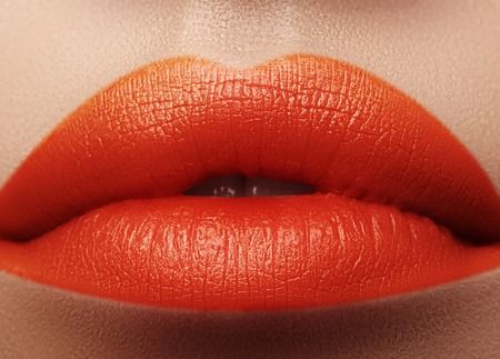 Close-up macro shot of female mouth. Sexy Glamour red lips Makeup with sensuality gesture. Orange colour, Full lipsの写真素材