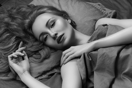 Beautiful Woman Sleeping while lying in Bed with Comfort. Sweet dreams. Sexy Beauty Model relaxing in Bedroom. Black and Whiteの写真素材