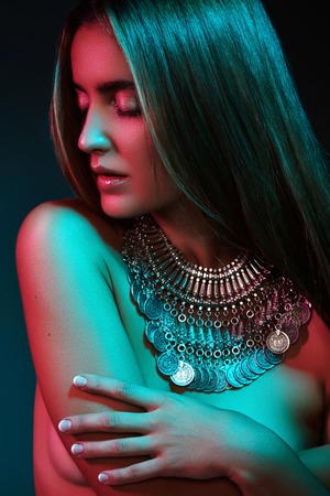Beautiful woman in a necklace. Model in jewelry from silver. Beautiful indian jewellery. Bright lights photo effectの写真素材