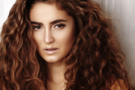 Beautiful young woman with long curly hairstyle, fashion jewelry with long brunette hair. Sexy girl in vogue style. Pretty arabian beauty portrait of female face. Indian style clothes, long dressの写真素材