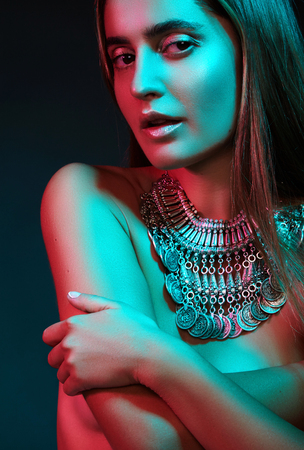 Beautiful woman in a necklace. Model in jewelry from silver. Beautiful indian jewellery. Bright lights photo effectの写真素材