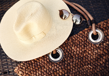 Holiday, Vocation, Travel, Lifestyle and Relax concept. Beach Hat, Boho Bag and Summer Sun Glasses. Brown Sunglass Accessories on woodの写真素材