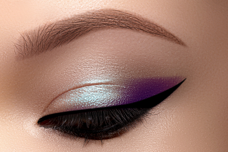 Celebrate Beautiful Macro Eyes with Smoky Cat Eye Makeup. Cosmetics and Make-up. Closeup of Fashion Visage with Liner, Purple and Cyan Eyeshadows.の写真素材