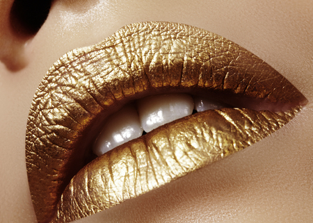 Beautiful closeup with female plump lips with gold color makeup. Fashion celebrate make-up, glitter cosmetic. Shine christmas style. Metalic makeupの写真素材