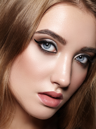 Beautiful Woman with Professional Makeup. Celebrate Style Eye Make-up, Perfect Eyebrows, Shine Skin. Bright Fashion Look. Black Liner, Shimmer Powder and Silver Eyeshadowsの写真素材