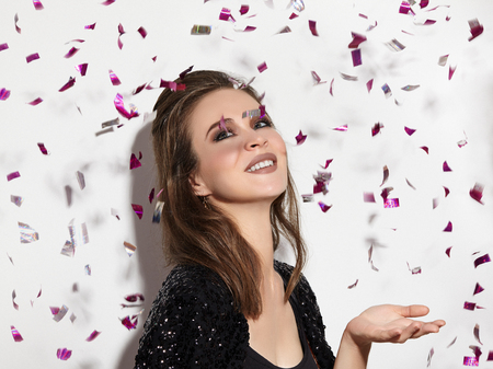 Party Time. Beautiful Happy Woman Smiling. Christmas Style in Confetti. Shiny Celebrate Look with Bright Fashion Make-up. Sexy Evening Makeupの写真素材