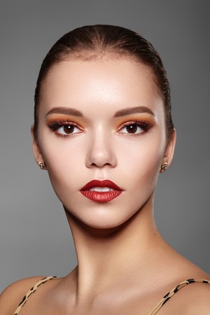 Beautiful Woman with Professional Makeup. Party Gold Eye Make-up, Perfect Eyebrows, Shine Skin. Bright Fashion Look with Red Lipsの写真素材