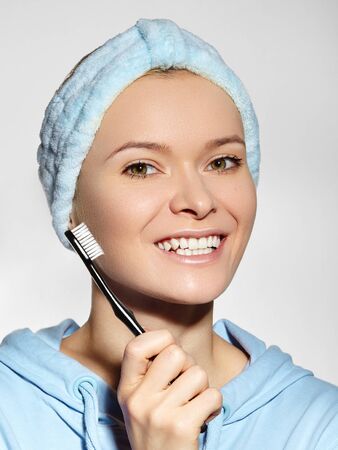Beautiful Woman with Great Teeth holding Tooth Brush. Daily Routine Teethcare Treatment for Perfect Happy Smile. Joyful Girl in Bath Headbandの写真素材