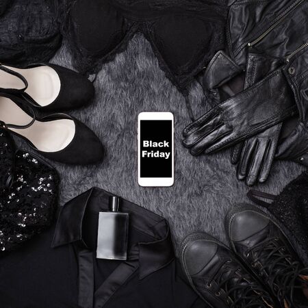 Black Friday Sale Fashion Dark Background. Black Clothes Flat Lay with Shoes, Fragrance, Lingerie, Dress, Gloves and Phone in center. Offer Shop Conceptの写真素材