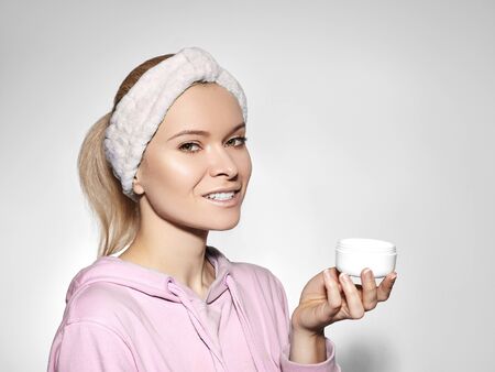 Happy woman with perfect skin applying day-night cream on cleansed face. Good concept of skincare, beauty industry, spa center and facial treatmentの写真素材