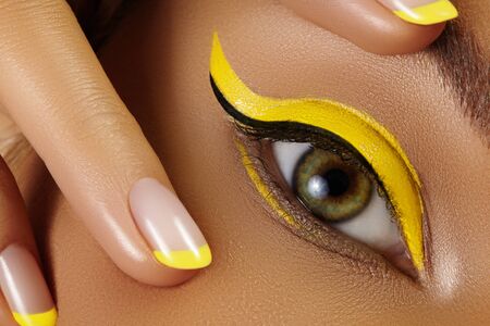 Beautiful macro close-up of female Eye with bright yellow Eyeliner Makeup. Neon Disco make-up and Fashion Manicure. Summer beauty styleCloseup macro shot of fashion liner eyes visageの写真素材
