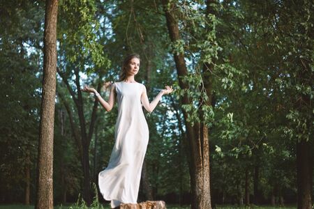Beautiful Woman Posing like Goddess in White Long Dress at Nature. Boho Style, Spirit Calm, Wellness and Self-making. Freedom and Relaxing. Soul Healthの写真素材