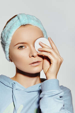 beautiful Woman with Fresh Clean Face use Cotton Pad for Make-up Removal. Pretty Girl in soft Headband. Morning Hygiene, Daily Beauty facial and skin care routineの写真素材