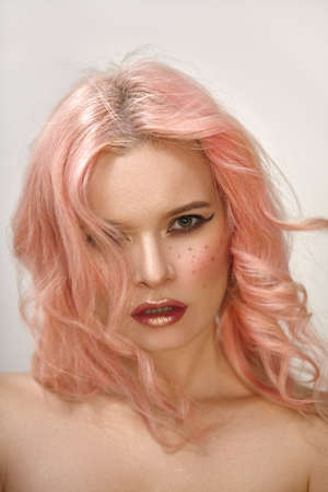 Beautiful woman with curly colored flying hair. Soft Girl style with sexy Make-up on face, red Lips and pink blush. Fresh wind of Fashionの写真素材
