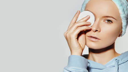 beautiful Woman with Fresh Clean Face use Cotton Pad for Make-up Removal. Pretty Girl in soft Headband. Morning Hygiene, Daily Beauty facial and skin care routineの写真素材