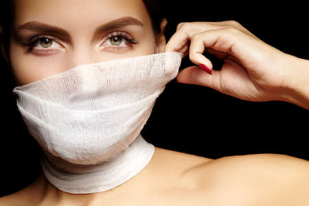 Beautiful woman with a bandage mask on face. Fashion eye make-up. Beauty plastic surgery or...