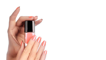 Beautiful Hands with Perfect Shiny Pink Manicure Holding Nail Polish Lacqueron White Background. Bright Nails. Copy spaceの写真素材
