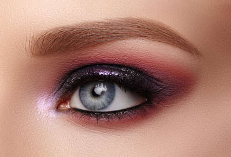 Beautiful Closeup Eye Make-up with Purple Glitter Shadows. Fashion Celebrate Makeup, Glowy Clean Skin, perfect Shapes of Brows. Shiny shimmerの写真素材