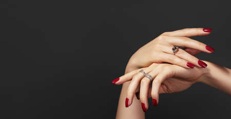 Beautiful glamor photo of elegant female hands with bright burgundy manicure on gray background....