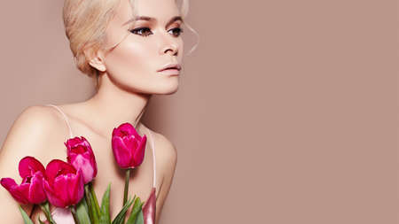 Beautiful sexy Blonde Woman with luxury retro Make-up. Girl with Spring Flowers Bouquet on Beige Background for any Celebrating. Fresh Style for Womans Day or Valentinesの写真素材