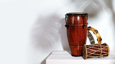 Composition of musical ethnic instrument. Maracas, tambourine, conga and ethnic drum. Percussion rhytm instruments are on white background with palm shade. Cuban sound, latin culture, samba and rumbaの写真素材