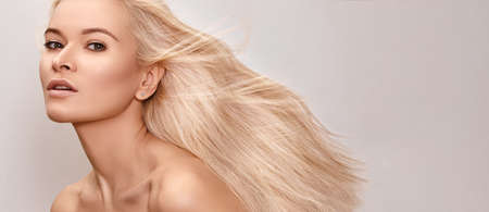 Beautiful woman with magnificent blond hair. Happy model face with windswept flying hair. Shiny long health hairstyle. Beauty and haircareの写真素材