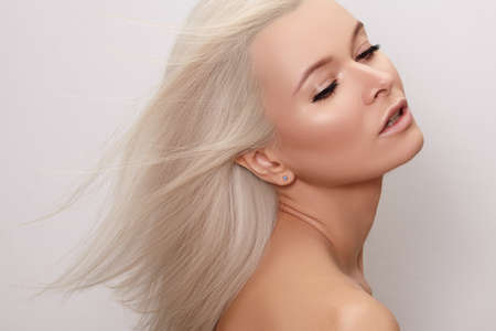 Beautiful woman with magnificent blond hair. Happy model face with windswept flying hair. Shiny long health hairstyleの写真素材