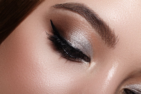 Close-up macro photograph of a female eye with elegant classic eyeliner. Well-groomed eyebrows, soft...