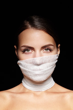 Woman with bandage mask covering face and neck, eyes with long lashes and thick brows. Perfect for Plastic Surgery Clinic, Cosmetology, dermatology, beauty and medical treatmentの写真素材