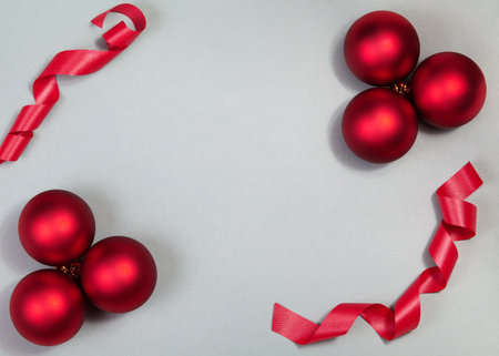 Top-down flat lay of red Christmas baubles and curled ribbon on neutral background, glossy ornaments and minimal styling creating festive holiday mood for seasonal campaigns. Xmas backgroundの写真素材