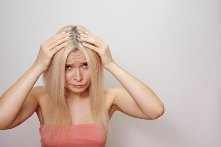 Emotive portrait of a blonde woman holding her head with both hands, expressive face and dramatic pose.の写真素材