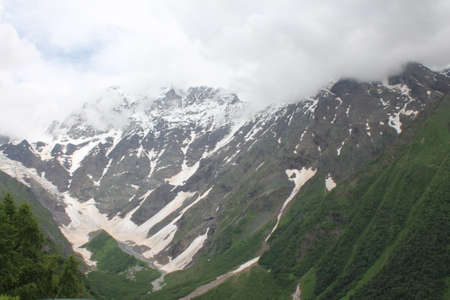 Mountain landscape with snow-capped peaks and clouds in the valley